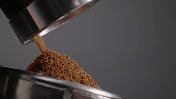 コーヒー粉を作る電気グラインダーフィルターホルダーに芳香豆を研削クローズアップ おいしい飲み物を作るためにポートフィルターに注ぐ地上コーヒー レストランでのプロのコーヒーメーカー — ストック動画
