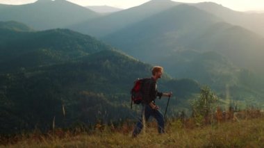 Strong man climb mountains hill nature. Walking tourist enjoy hike on vacation. Young hipster guy backpacking using trekking poles on summer recreation. Outdoors activity healthy lifestyle concept.