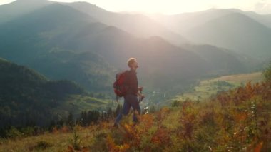 Active man walk mountains landscape. Sporty tourist hiking using trekking poles in morning sunrise. Backpacking hipster enjoy wanderlust travel lifestyle. Summer holiday activity recreation concept.