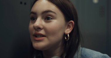 Çekici, neşeli bir kızın üniversitede erkek arkadaşıyla konuşması. Kapalı dolaba yaslanmış, kulaklıklı, gülümseyen bir öğrencinin portresi. Mutlu gençler arkadaşlarıyla sohbet ediyor.