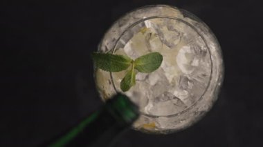 Şişeden akan su buzlu limonatayı yakınlaştırır. Limonlu soda ve naneli makro yavaş çekim. Lezzetli bir diyet içeceği, siyah arka plan manzarası. Kokteyl konsepti hazırlanıyor 