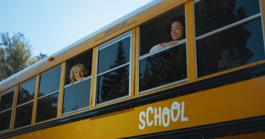 Sabahları otobüsün camından bakan iki okul çocuğu. Okul otobüsünde bekleyen çok ırklı gülümseyen ilkokul öğrencileri okula gitmeye hazırlar. Neşeli kız arkadaşı kamerayla bakan kıvırcık çocuk..