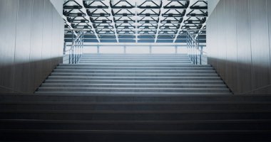 Boş okul merdivenleri büyük salona çıkıyor. Çelik parmaklık manzaralı temiz merdiven. Geniş pencerelerde parlayan güneş ışığı. Eğitim kurumunun tavanında lambalar var. Modern inşaat kavramı.
