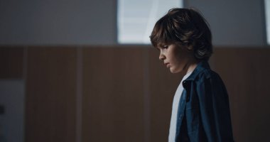 Okul koridorunda yalnız yürüyen düşünceli bir öğrenci. Kapalı sınıf kapılarına yaklaşan endişeli üzgün öğrenci. Mutsuz adam sorunlara odaklanmış. Çocukluk konseptinde yalnızlık.