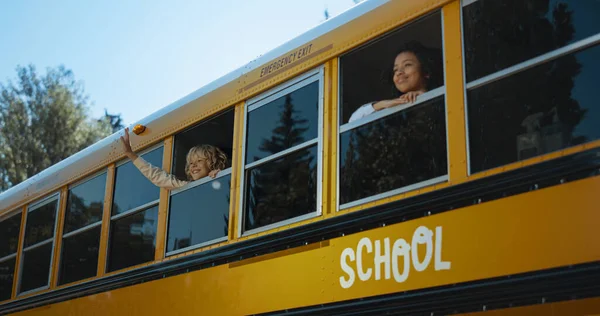 Two Multiethnic School Children Looking Out Yellow School Bus Window Stock Image