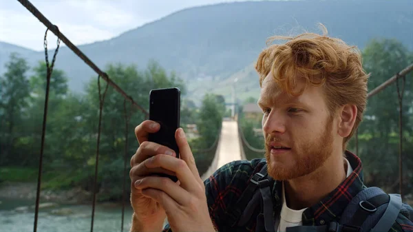 Tourist hipster taking video on mobile phone close up. Traveler make photo of nature view countryside landscape. Redhead joyful backpacker spend summer vacation. Modern technology travel fun concept.