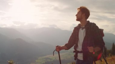 Closeup energetic hiker walk nature on mountains landscape. Hipster using trekking poles on tourism activity. Active backpacker enjoy look serene view on vacation. Wanderlust youth leisure concept.