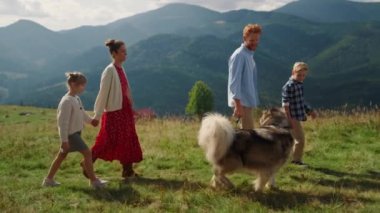Happy family walk with pedigree dog on beautiful mountain slope sunny day. Beautiful woman holding daughter hand enjoying trip on summer nature. Father walking fluffy pet with preteen son outdoors.
