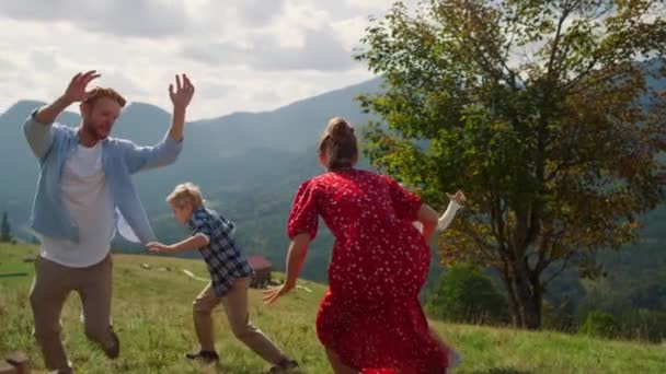 Παιχνιδιάρικη Οικογένεια Τρέχει Στην Καταπράσινη Πλαγιά Του Βουνού Ηλιόλουστη Μέρα — Αρχείο Βίντεο