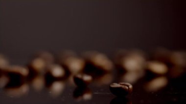 Yakın plan kahve çekirdekleri yüzeyde seçici bir şekilde duruyor. Güçlü enerji içeceği hazırlamak için kahverengi aromatik tanelerin makro görüntüsü. İçeriye birkaç taze kafein tohumu yerleştirildi. Kahve hasadı.