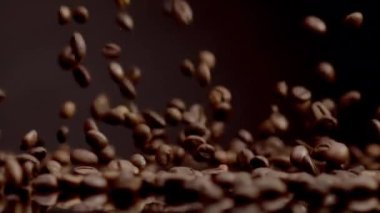 Organic coffee beans falling on dark backdrop close up. Beautiful roasted coffee grains background. Aromatic fresh caffeine seeds pouring super slow motion. Natural crop for energetic morning beverage