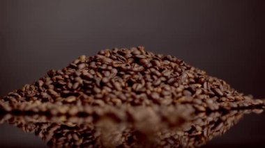 Coffee beans heap background close up. Roasted caffeine grains super slow motion. Aromatic fresh crop for making perfect energetic espresso cappuccino. Selective focus on brown gourmet coffee seeds.