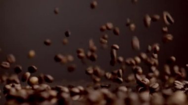 Brown coffee grains falling surface bouncing closeup. Dawnfall roasted aromatic seeds in super slow motion. Fresh beans pouring table. Perfect natural ingredient for making energetic morning beverage 