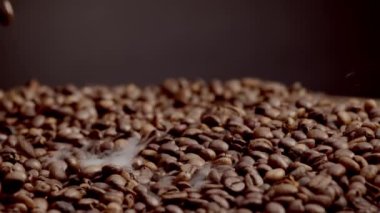 Kavrulmuş kahve çekirdekleri yakından pişiyor. Kahverengi aromatik taneler ağır çekim yığını üzerine düşüyor. Gurme Arabika 'yı sabah içkisi için hazırlıyorum. Enerji içeceği için mükemmel kokulu malzeme..