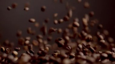 Coffee seeds downfall close up. Roasted brown beans falling down on table bouncing. Aromatic fresh grains pouring table in super slow motion. Caffeine harvest for energetic beverages dark background.