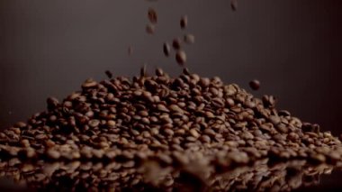 Coffee beans pouring on top heap close up. Roasted caffeine grains falling down super slow motion. Brown aromatic fry coffee seeds background. Perfect ingredient for energetic morning beverage.