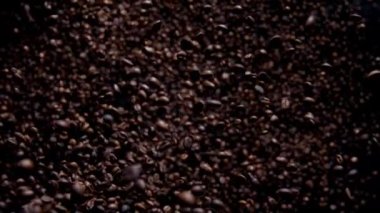 Flying roasted coffee beans in super slow motion. Fragrant fresh arabica seeds harvest falling on dark background close up. Explosion aromatic brown grains for tasty morning drink. Energy drink.