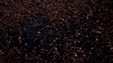 Perfect delicious coffee grains flying in super slow motion. Roasted fresh beans falling on dark background. Beautiful view downfall tasty brown coffee seeds. Premium ingredient for morning drink.