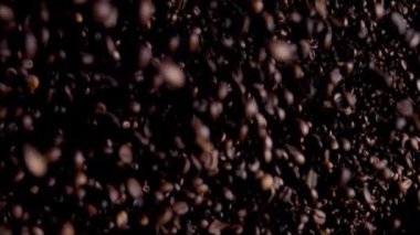 Fantastic downfall of large heap coffee grains on dark background. Roasted fragrant beans for aromatic drink falling down in super slow motion. Tasty seeds natural organic arabica flying close up.