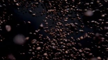 Magic view falling roasted coffee beans on dark background. Fresh aromatic seeds downfall in super slow motion. Tasty premium coffee grains flying close up. Delicious morning drink concept. 