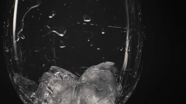 冷たいブロックがガラスを閉じます 超スローモーションで透明なドロップワイングラスの中に氷のキューブスロー さわやかな飲料マクロ黒の背景 ドリンクやカクテルのコンセプトの準備 — ストック写真