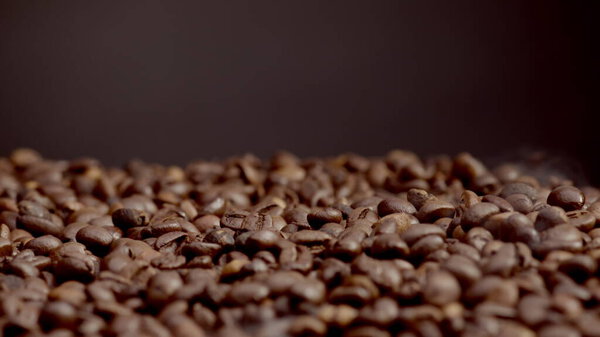 Closeup roasted coffee seeds background. Fragrant seeds pouring down on roaster. Brown beans falling in super slow motion. Perfect aromatic arabica preparing for grinding. Morning drink concept.