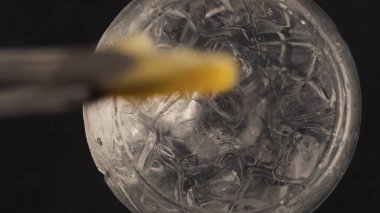 Forseps limonlu su bardağını yakın plan çeker. Makro yavaş çekimde meyve dilimli soğuk su. Yaz içeceği, kıskaçlar ve bar ekipmanlarıyla hazırlandı. Kokteyl süreci konsepti yapılıyor