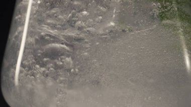 Buz köpüklü nane likörü. Şarap kadehini yavaş çekimde yakın çekim. Köpüklü maden suyuna, temiz cam makro manzaralı bitkiler damlatıyor. Organik antioksidan detoks ev yapımı kokteyl konsepti