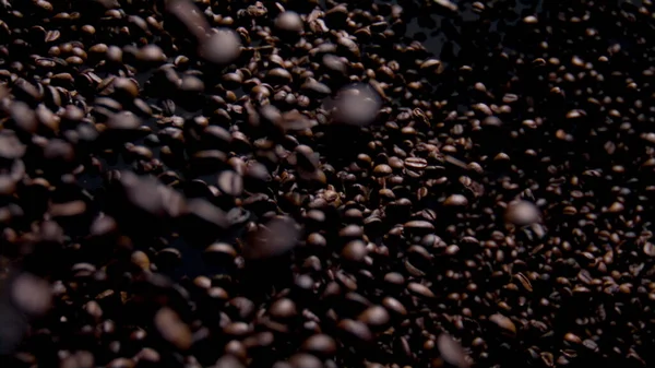 Aromatic coffee grains fly on camera close up. Super slow motion of fragrant brown beans falling on dark backdrop. Exciting view delicious coffee seeds downfall. Strong taste energy concept.