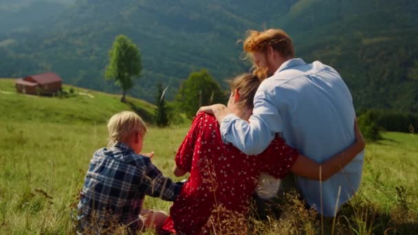 Loving Parents Hugging Sitting Son Mountain Slope Sunny Day Relaxed — Video