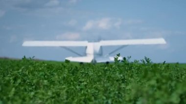 Lightweight airplane standing high green grass with spinning propeller sunny day. Small white aircraft starting engine preparing to flight. Private plane ready to fly in cloudy sky. Travel concept.