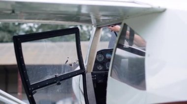 Professional aviator exiting cabin airplane after long flight on aerodrome. Aviation instructor leaving aircraft cockpit after successful landing. Pilot finish training with air transport cloudy day.