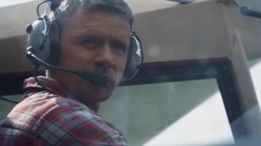 Closeup airplane pilot face wearing headset with microphone sitting small plane cabin. Focused aviator making preflight checking private aircraft. Professional airman preparing air transport to flight
