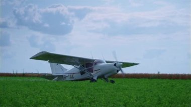 Lightweight airplane standing green field with working propeller preparing to flight. Small private plane with spinning blades parked on grass airfield. View of modern aircraft in front beautiful sky.
