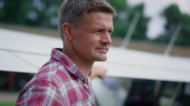 Portrait of thoughtful pilot standing in front white wing airplane looking sky before long flight. Focused airman posing thinking about aeronautics hobby on green aerodrome closeup. Aviation concept.