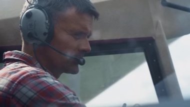 Portrait of professional aviator wearing headset in aircraft cockpit analyzing plane condition before flight. Skillful pilot man preparing to taking off sitting cabin modern airplane close up.