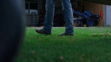 Closeup unknown aviator legs walking around small private plane before sitting in cabin. Unrecognizable pilot going to airplane on green grass ready fly from aerodrome. Aviation passion concept.