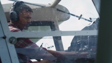 Serious airman sitting in airplane cabin preparing for training flight close up. Focused professional aviator starting engine in private aircraft cockpit. Pilot turning on buttons control panel.