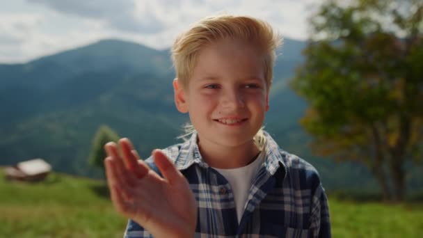 Милий Усміхнений Хлопчик Махає Рукою Камеру Стоїть Зеленому Лузі Крупним — стокове відео
