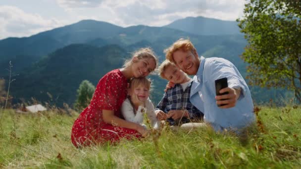 Positive Family Taking Selfie Cellphone Sitting Green Grass Mountain Hill — Stockvideo
