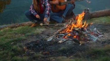 Romantic couple camp together in mountains nature closeup. Young tourists play guitar music song outside. Love millennials relax on honeymoon. Happy family have fun at picnic bonfire. Leisure concept.