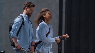 Ofis yöneticileri çevre dostu araçlarla işe gidip geliyorlar. Kurumsal insanlar. Keyifli yöneticiler ellerinde elektrikli scooterla şehir merkezinde yürüyorlar. Sakallı adam gülümseyen kadın güneşli sokağa çıkıyor.