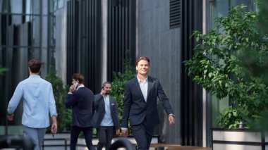 Memnuniyet duyulan iş adamı şehir merkezinde takım elbiseyle uzaklığı arıyor. Yakışıklı, gülümseyen avukat CEO modern iş merkezine gidiyor güneşli bir sabah. Zengin finansal uzman yaşam tarzı konsepti.