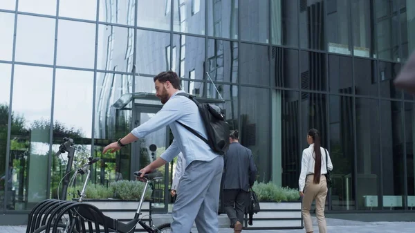 Manager riding bicycle leaving office workplace. Modern city mobility vehicle. Serious bearded man financial assistant take rental bike on parking. Confident ceo director going eco-friendly transport.