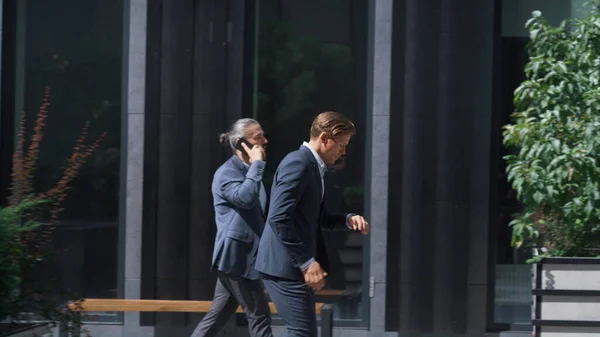 Confident businessman late for meeting running downtown street in sunny morning. Focused handsome project manager director going to important client in hurry. Serious agent rushing to office in suit.