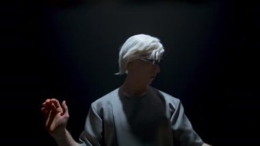 Guy using vr headset in dark room. Focused player gesturing touching invisible objects in light. Futuristic blonde man immersing virtual reality in metaverse goggles. Cyber gamer swiping 3d simulation