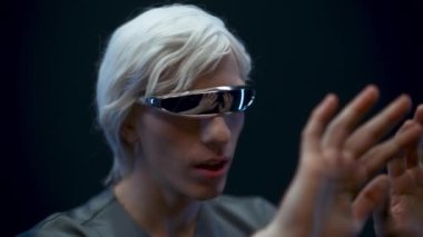 Impressed vr headset man enjoying augmented reality closeup. Astonished excited gamer amazed touching arms with open mouth black background. Guy experiencing virtual metaverse gaming first time 