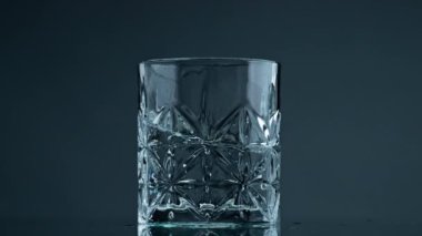 Glass water waves moving in beautiful cup closeup. Transparent liquid splashing in textured container at dark background. Still cool beverage purified product in jug. Healthy lifestyle balance concept