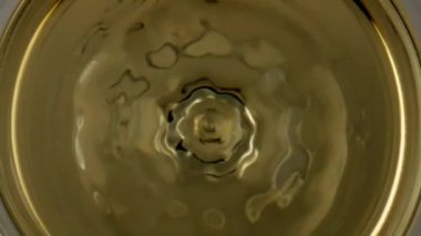 Wine drop splashing goblet closeup. Smooth liquid surface rippling waving in transparent cup. Cool chardonnay drop falling golden crystal clear liquor. Viticulture elegance dining enjoyment concept.