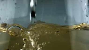 Bubbling wine pouring glass goblet closeup. Gold sparkling beverage filling cup. Diverse air bubbles rising flowing fizzy cool alcohol drink. Tasty romantic evening anniversary celebration concept.